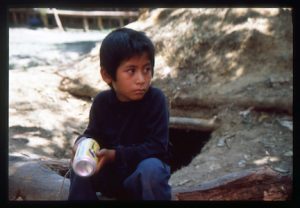 Boy sits in front of bunker at Indigenous Zapatista EZLN headquarters in La Realidad, Chiapas, Mexico by Orin Langelle